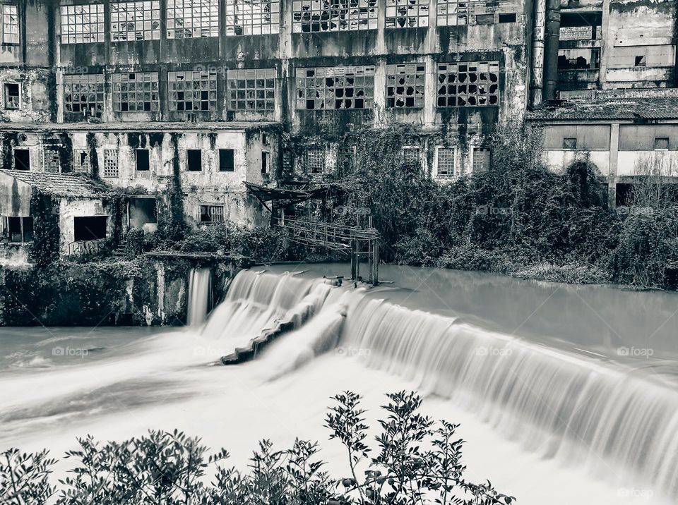 Old abandoned factory next to a weir in black & white