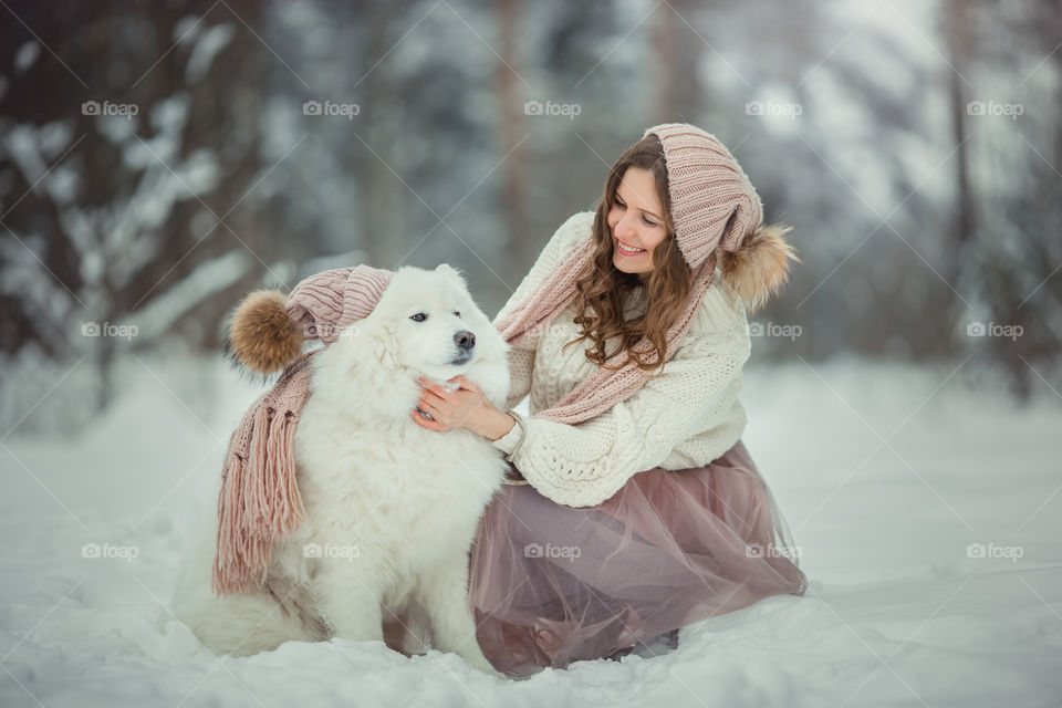 Beautiful woman with dog samoyed in winter forest
