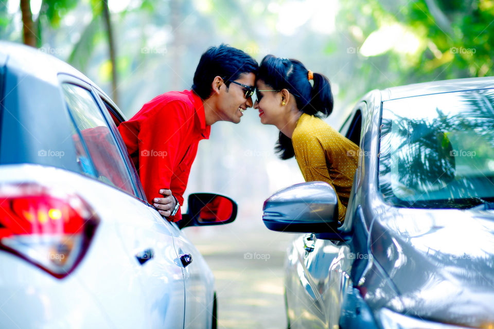 Young couple looking at each other through car window