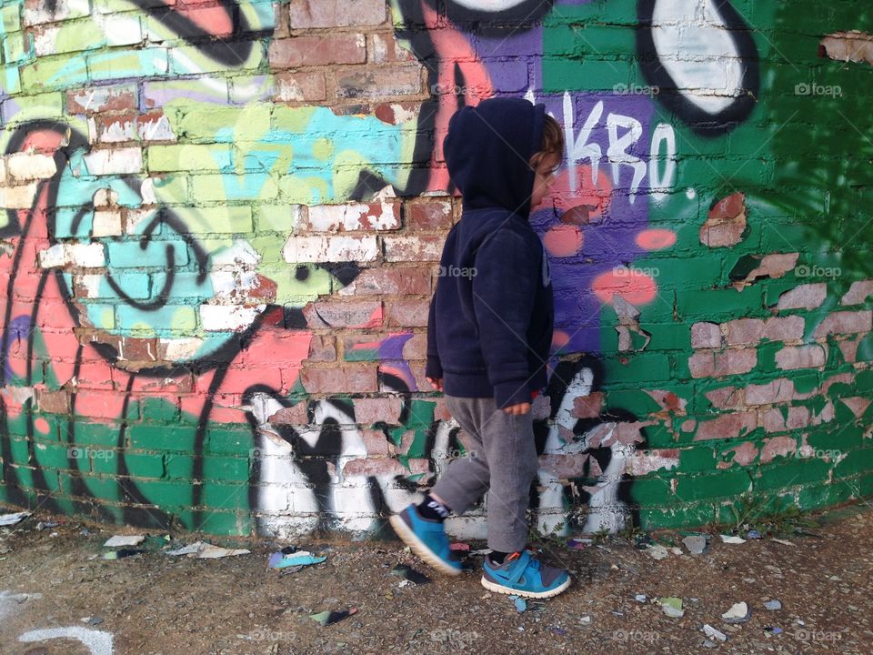 Three-year-old boy walking by graffiti.