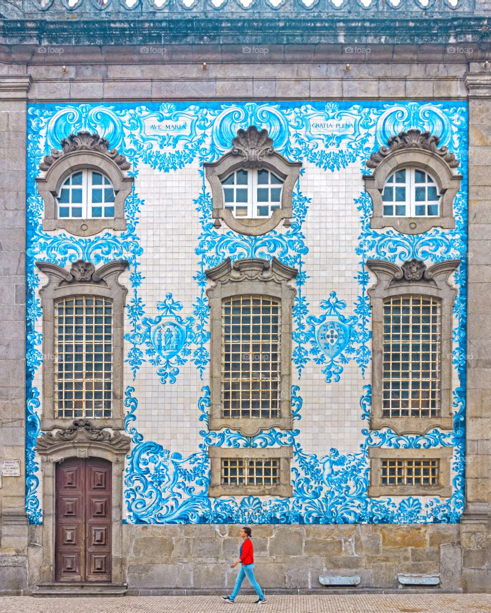 Girl walking against blue tile wall of church in Porto, Portugal