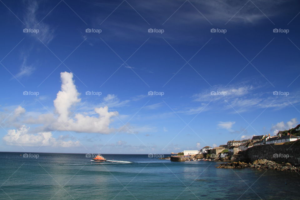 Lifeboat Day. An RNLI lifeboat leaves a Cornish fishing village behind on a beautiful summer evening.