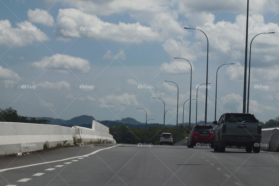 Beautiful day for traveling with cumulus clouds and blue sky and empty road ahead