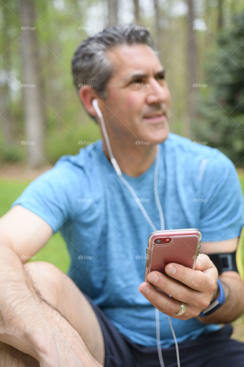 Man with earbuds and his phone after a workout 