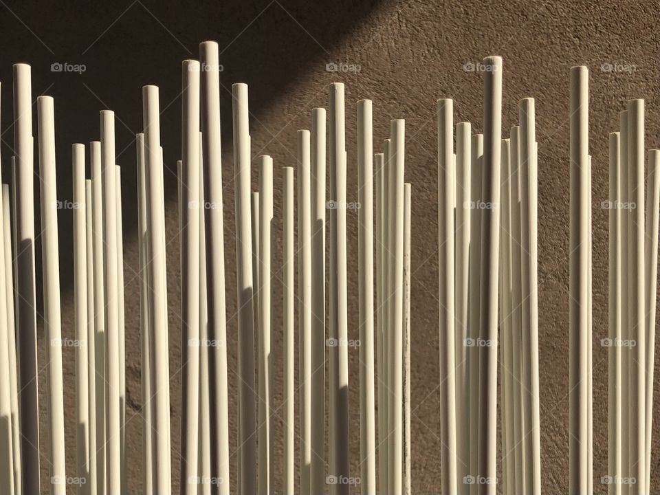 White sticks set against rustic wall with lights and shadows