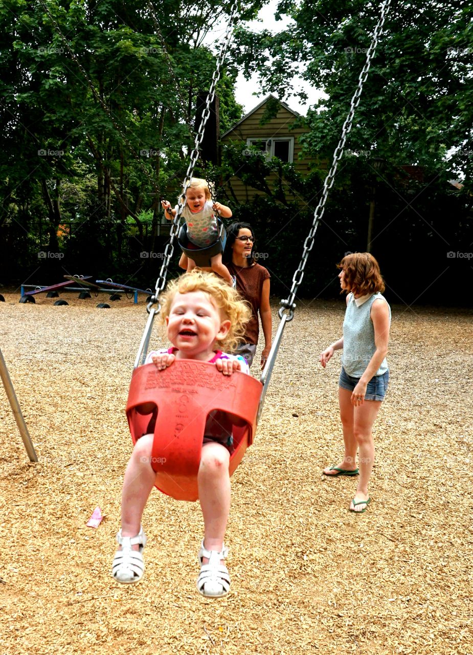 Children enjoying on swing in playground