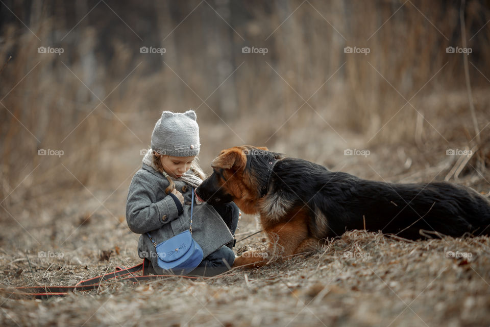 Little girl with German shepherd young male dog walking outdoor at spring day