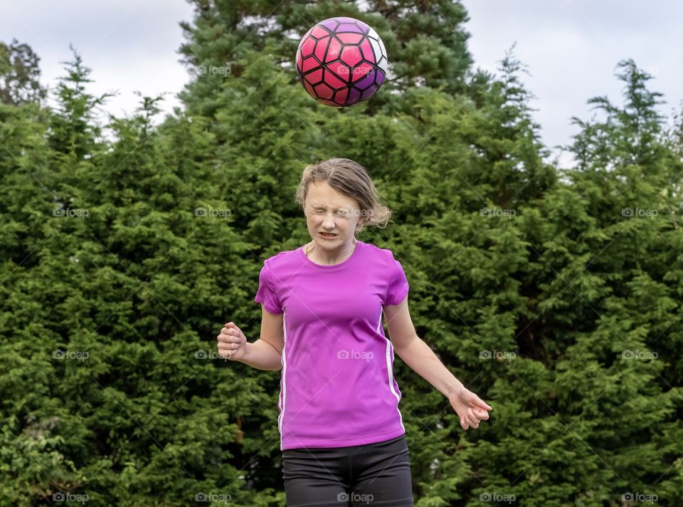 Soccer player hits soccer ball off her head - girl practices her soccer moves