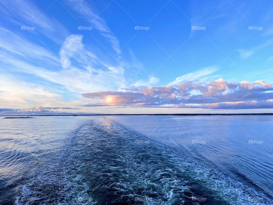 Beautiful tranquil sunrise landscape over the sea water surface with the foaming cruise ship trail 