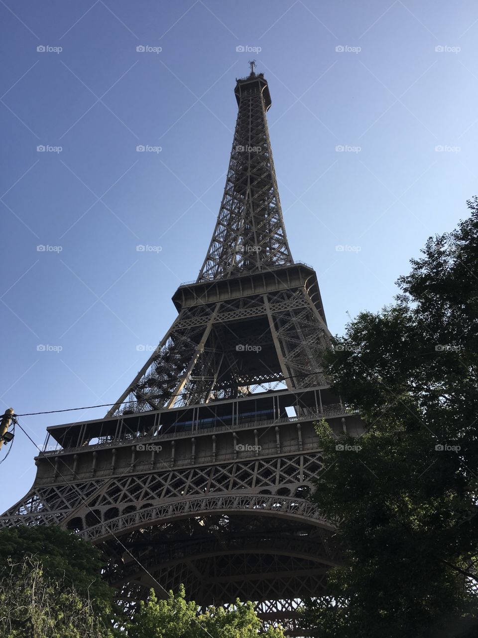 A shot of the Eiffel Tower. The sky is clear and blue. The Eiffel Tower seems to touch the sky.