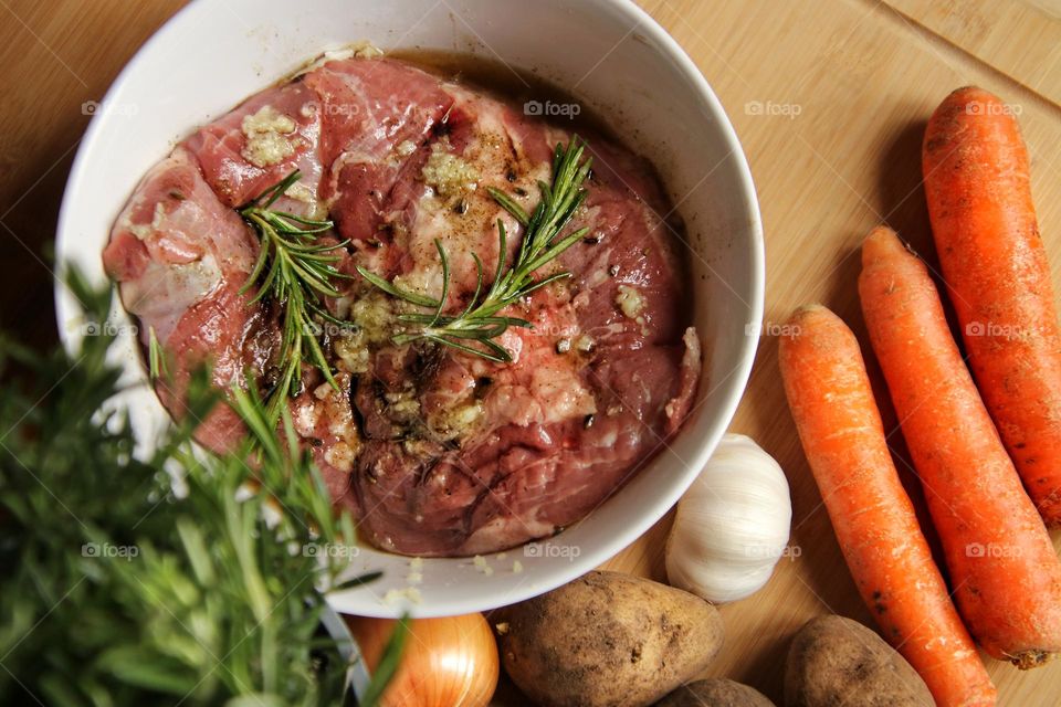 Close up of raw meat with rosemary and vegetables