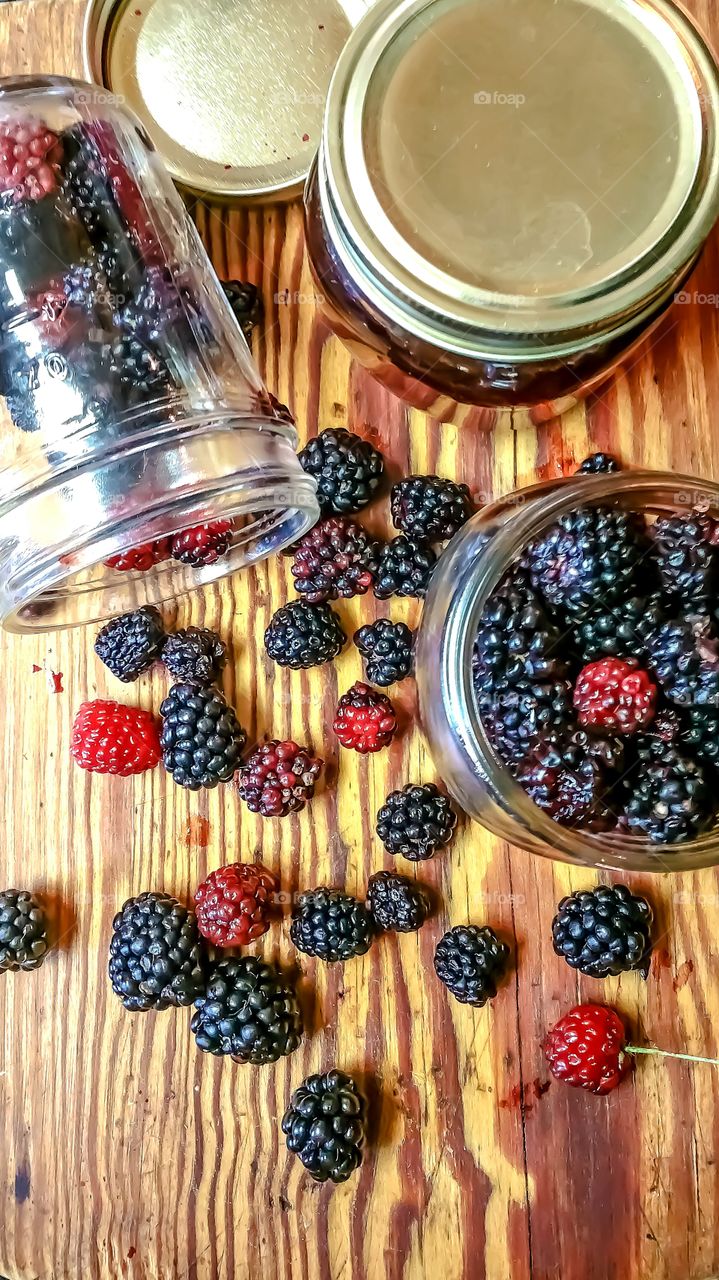 fresh wild berries in jars on wood cutting board
