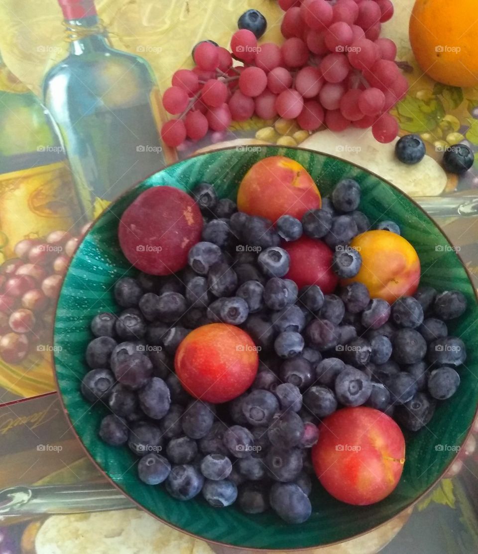 this ball consist of baby peaches blueberries grapes and lemon with placemats underneath the fruit