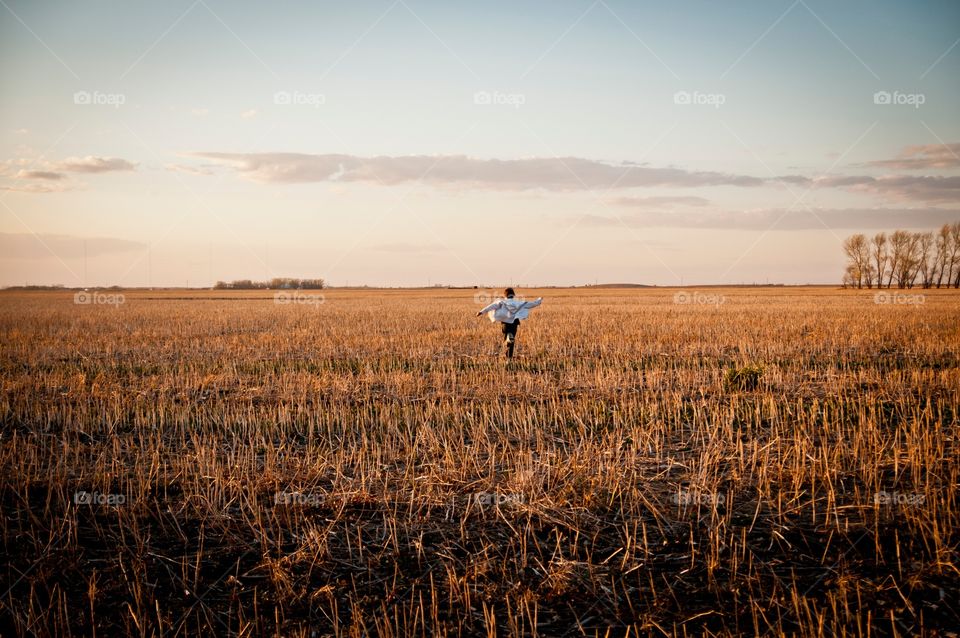 Boy in field running through wheat 