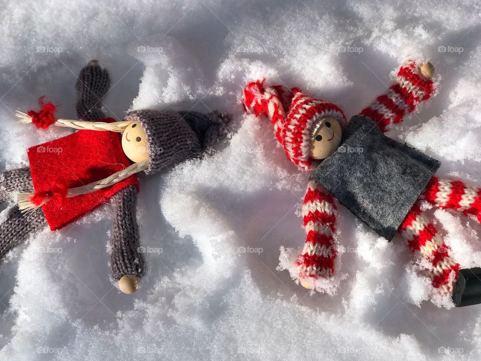 two wooden man girl and a boy lying in the snow, play a scene of love and happiness