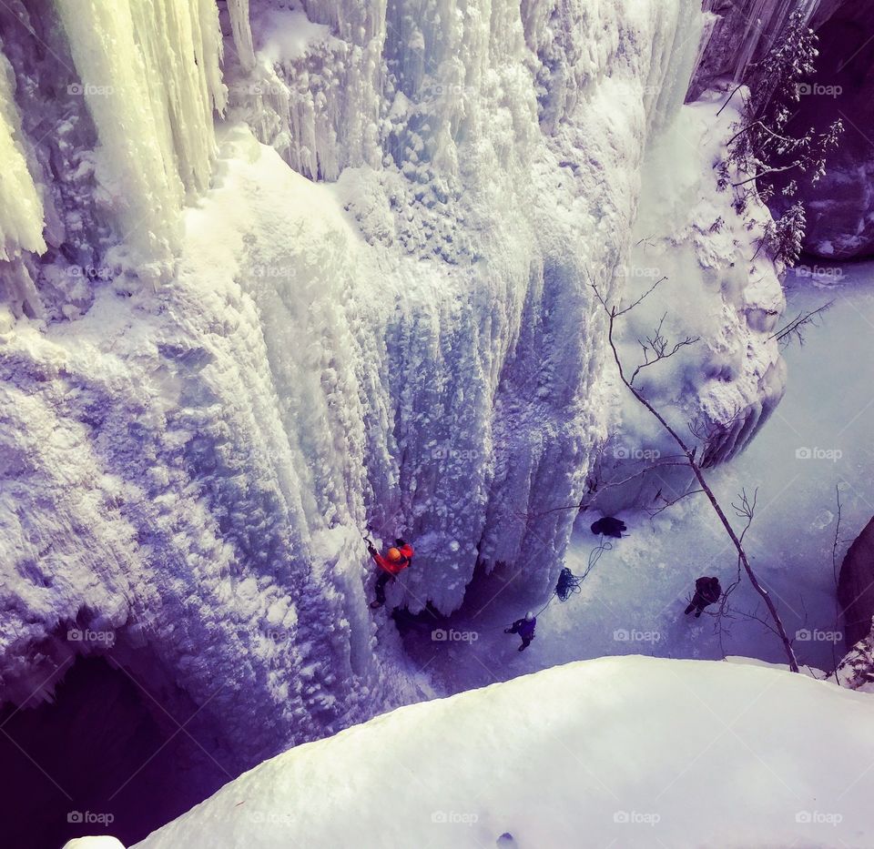 Ice climbers digging in with their ice picks and crampons as they hike an ice wall during the winter in Jasper National Park