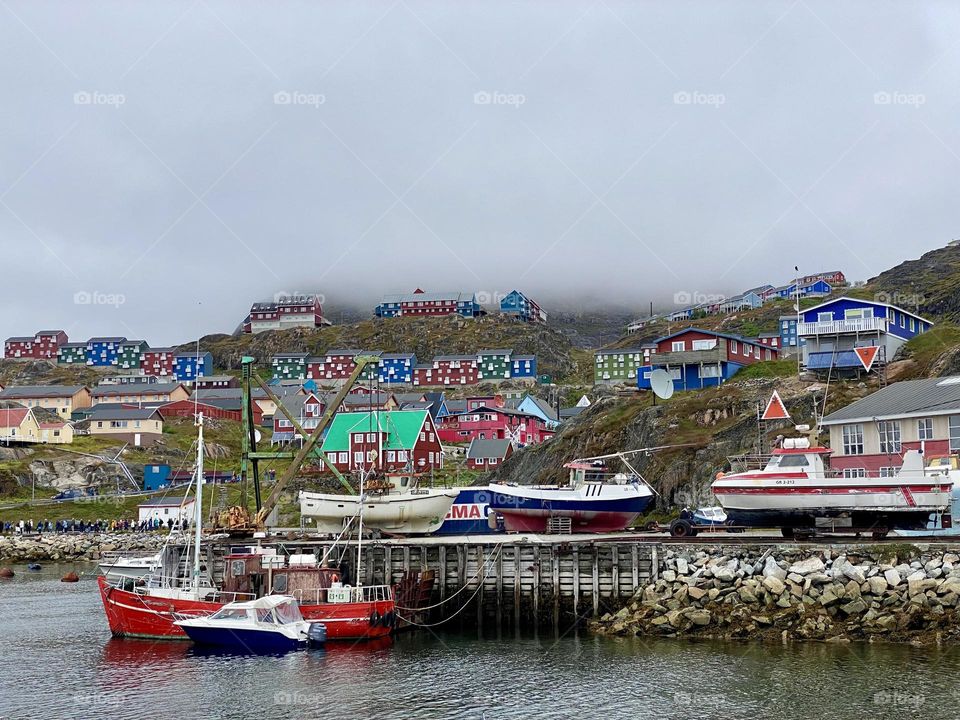 Several boats and a hillside of brightly painted houses in a small town in Greenland 