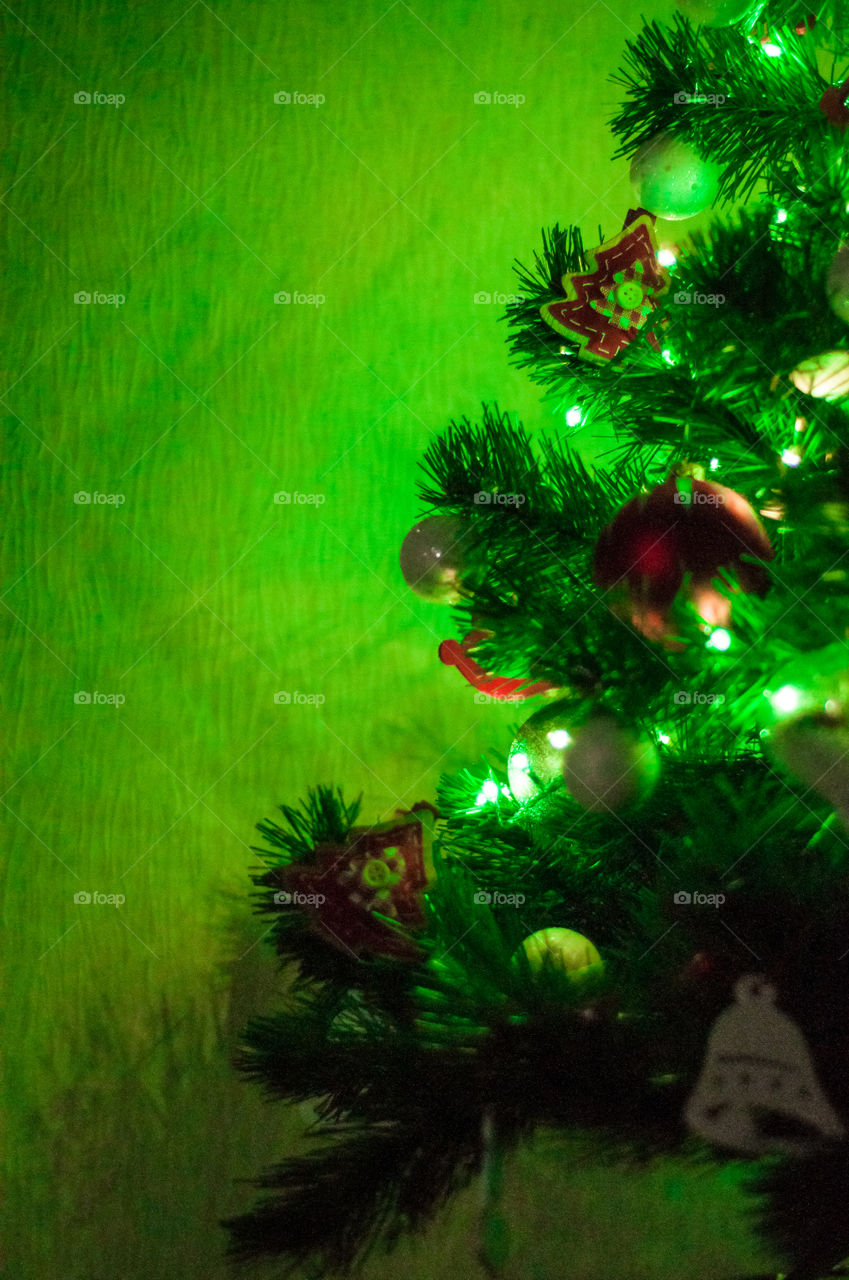 Part of Christmas tree in green light and space for text 