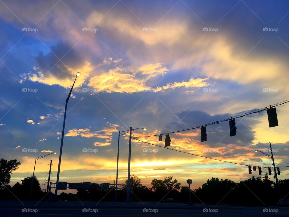 A vivid urban sunset featuring golds, oranges, and blues.