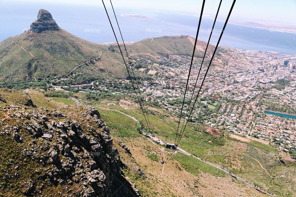 Metal wires transporting cabins up the Table Mountain in Cape Town South Africa seen from above down to the cable station and the city . Atlantic Ocean seen in the background. 