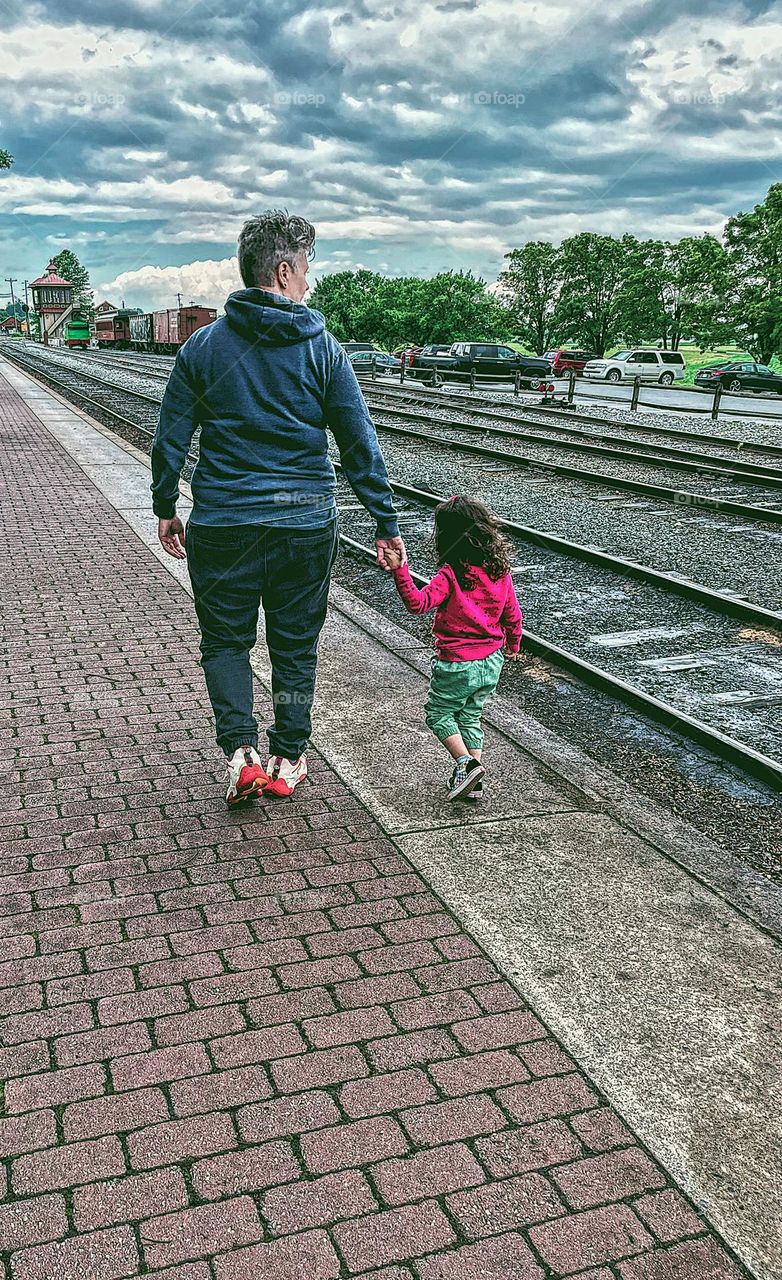 Mother and daughter walk along railroad tracks holding hands, tender moments with toddlers, mother and toddler enjoying the sightseeing opportunities, railroads and kids in Pennsylvania 