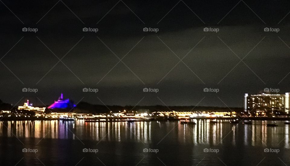 Looking across the lake to the Magic Kingdom.  Space Mountain is lit up in blue, while the white lights are reflected on the water. 