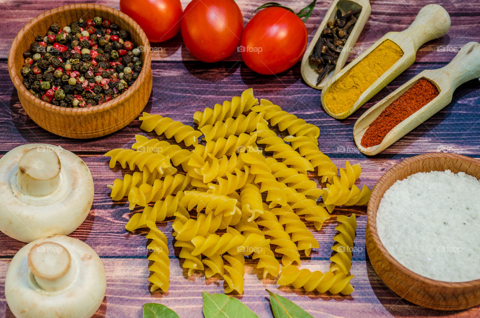 Raw pasta with ingredients and wooden accessories