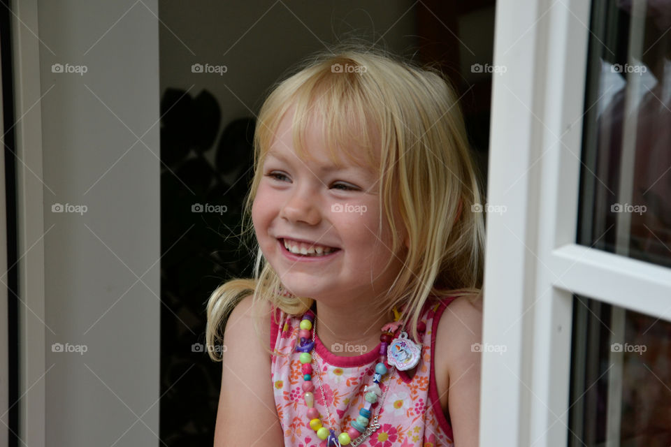 Happy little girl of five years old looking out the window.