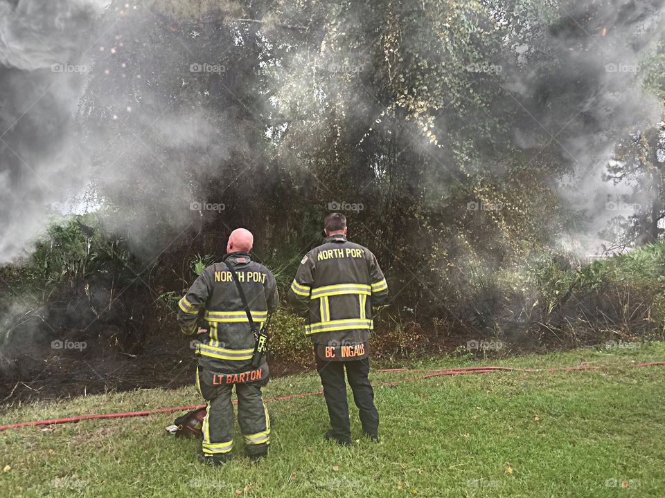 Brave firefighters. Brave firefighters surveying the site, watching the remaining smoke.