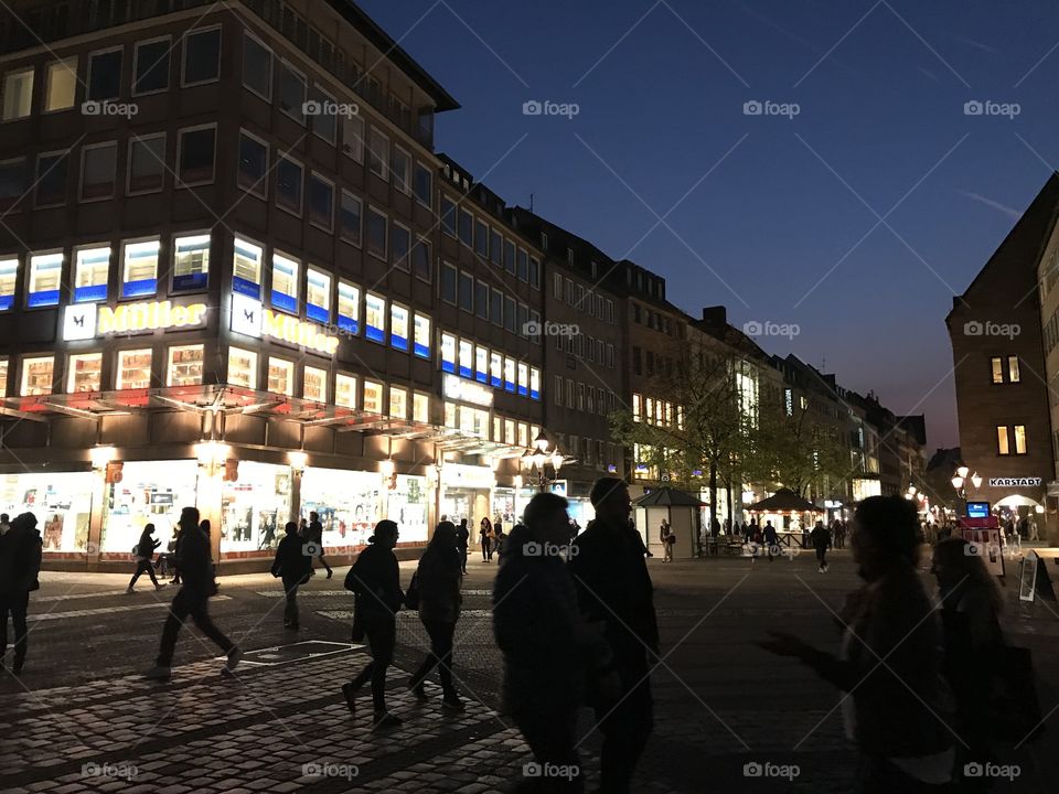 evening city in the background lights of shop windows, in the foreground silhouettes of people walking