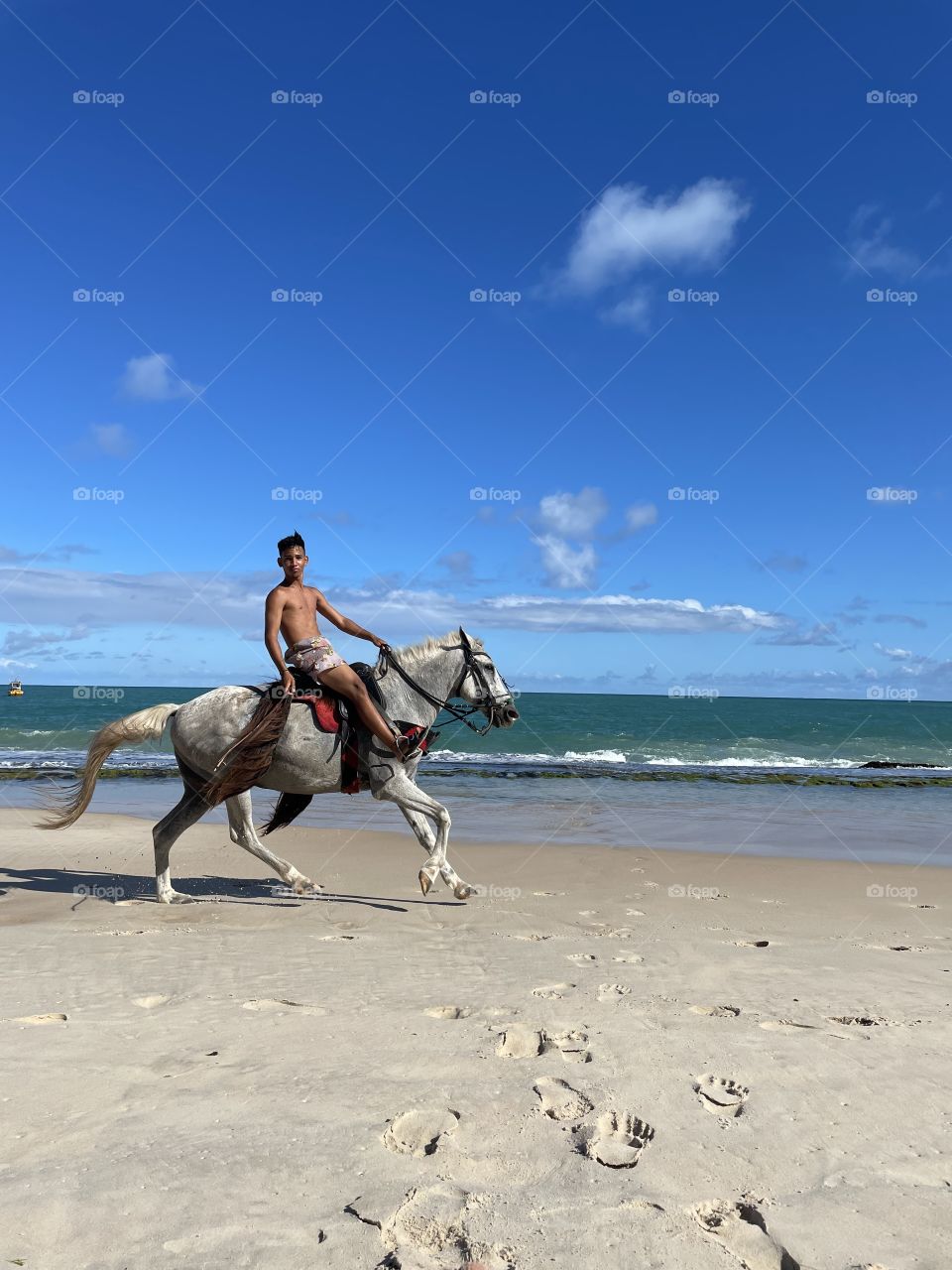 Man smiling on horseback on the beach