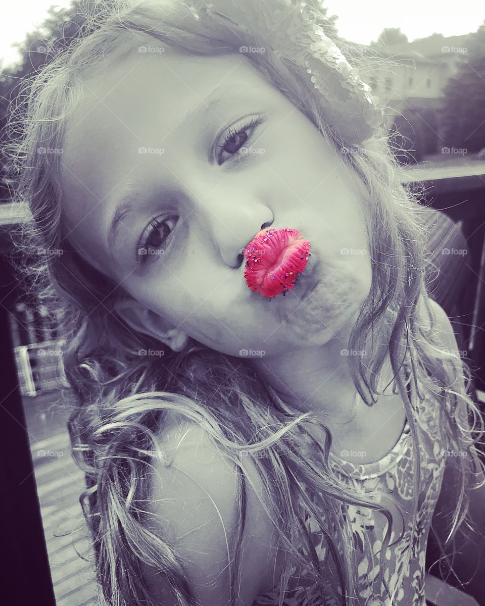 Black and white photo of a little girl with bright pink glittery lips. Pucker up!