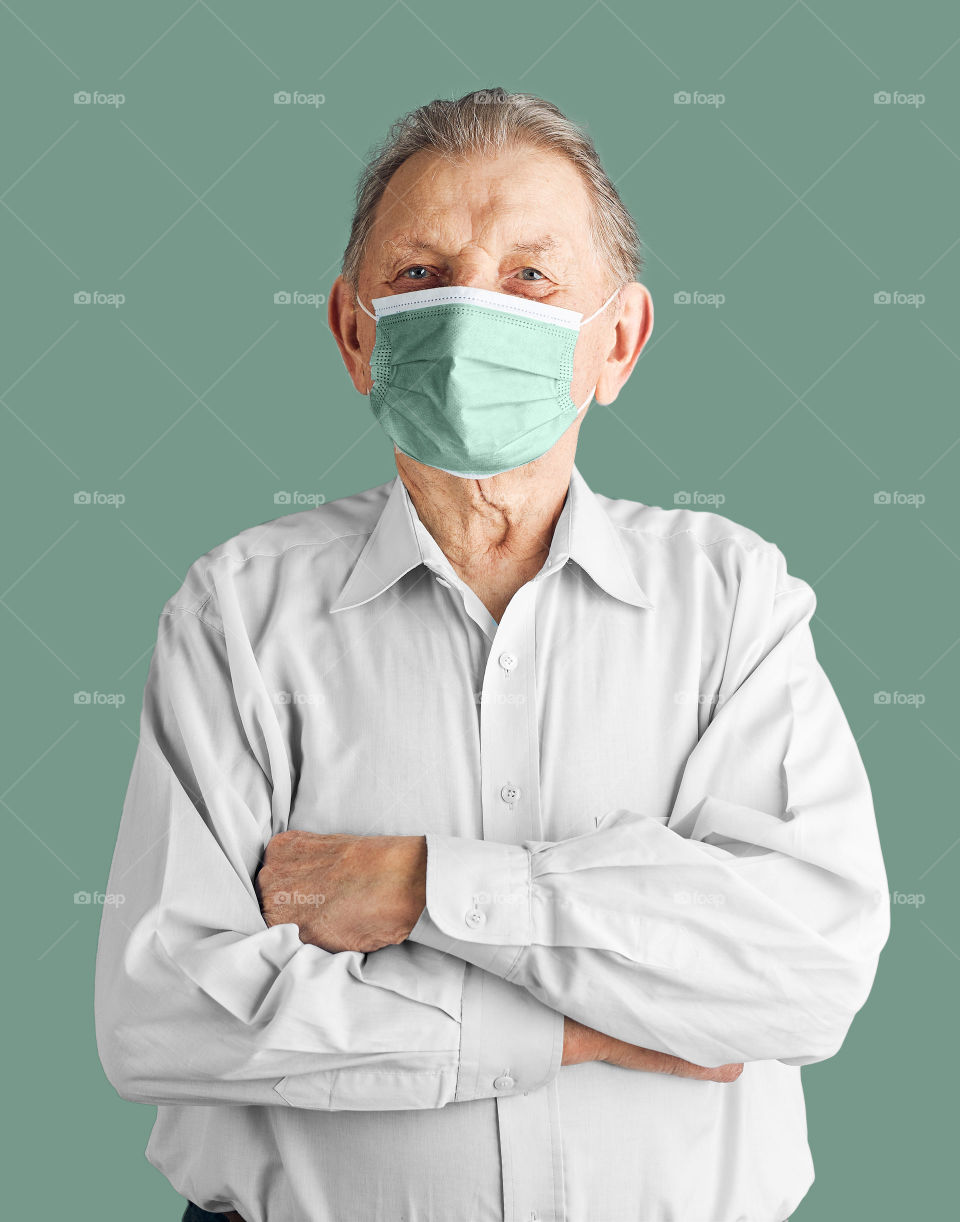 Old aged senior male patient with face mask. Wearing coronavirus covid-19 protection medical mask during the pandemic