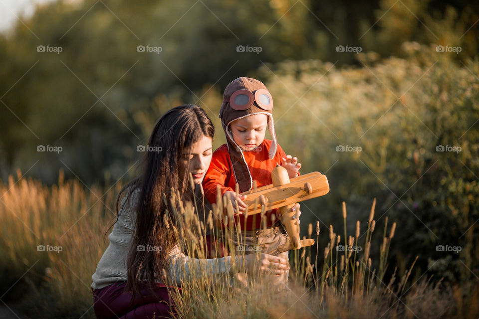 Mother and son with wooden plane at sunset