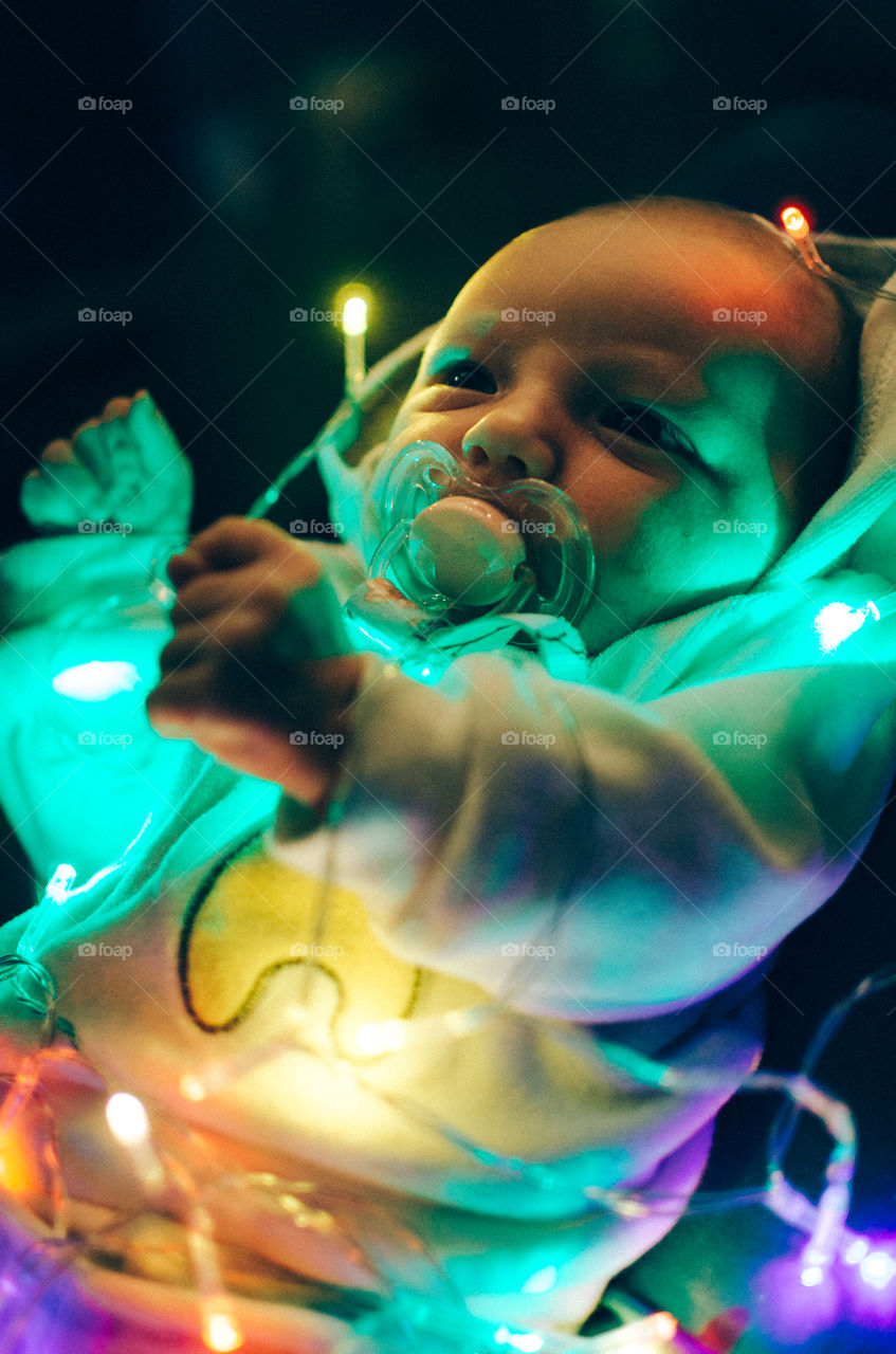 Close-up baby on illuminated crib