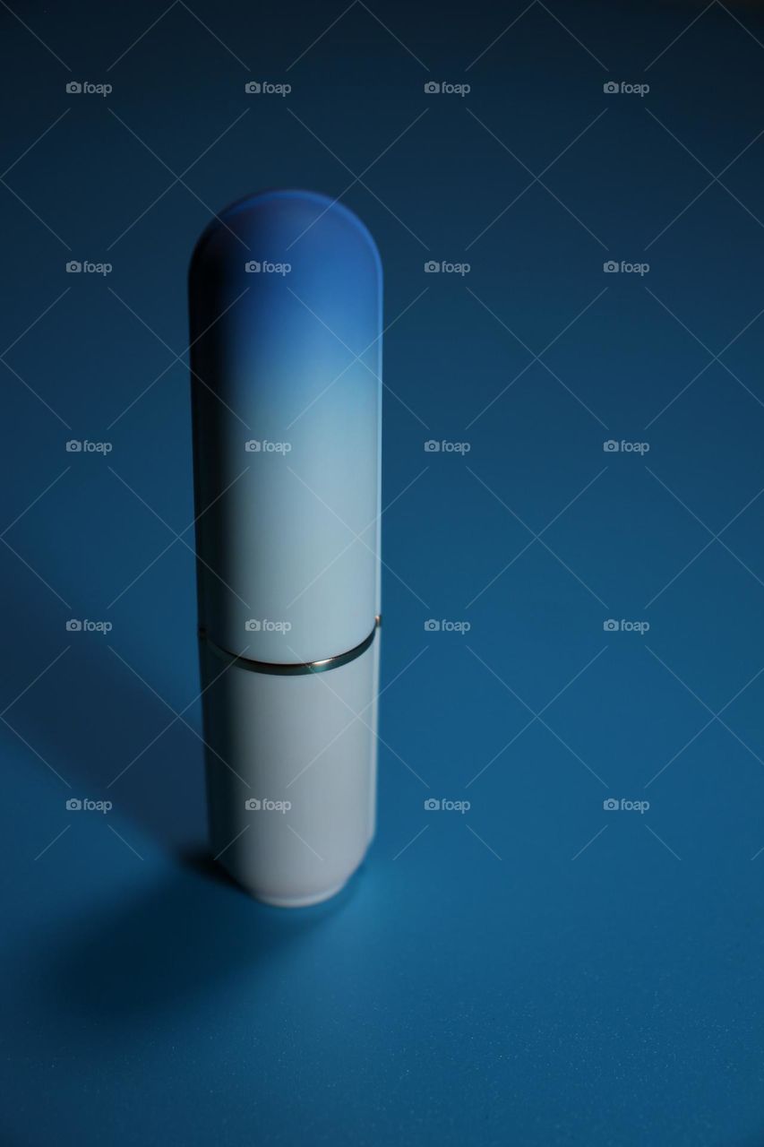 lipstick on a blue background, case on a blue background, perfume on a blue background, pen on a blue background