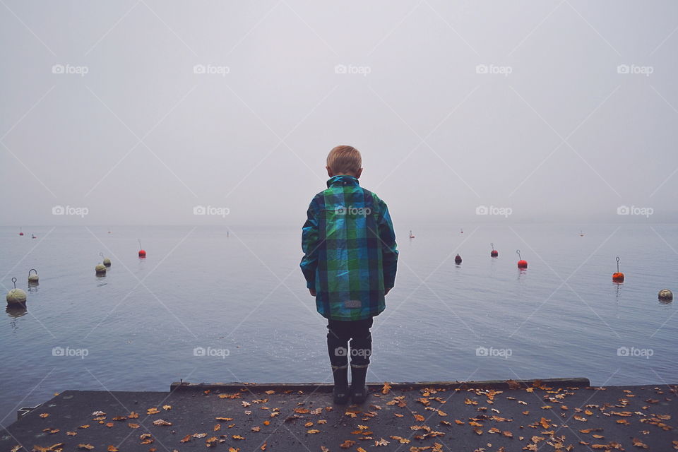 Boy looking out at the misty lake