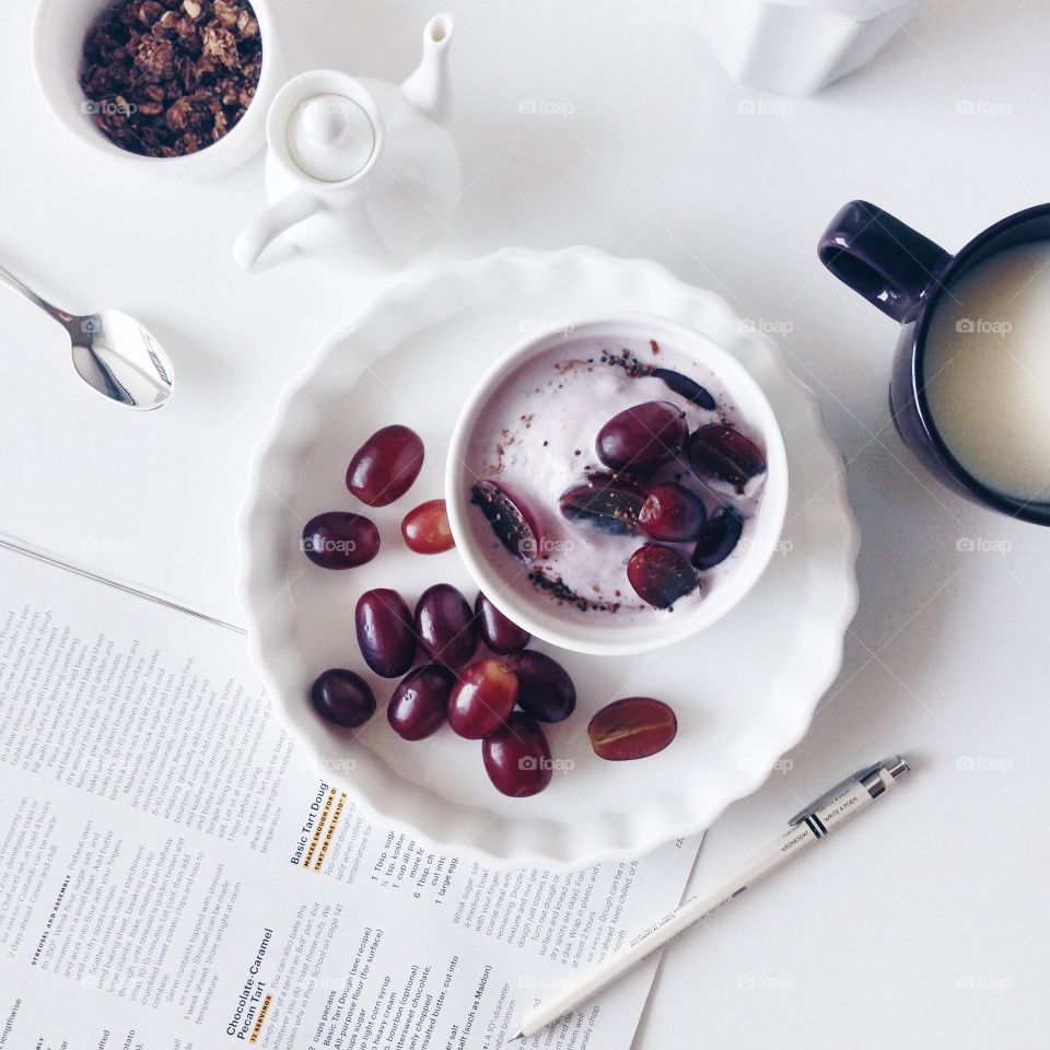 Healthy breakfast with greek yogurt, purple grapes, cocoa granola and milk.