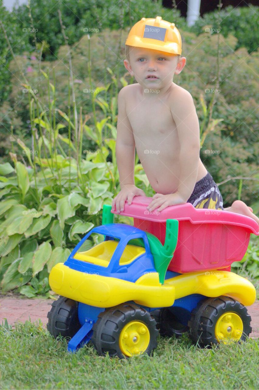 Young boy playing on toy dump truck at outdoors