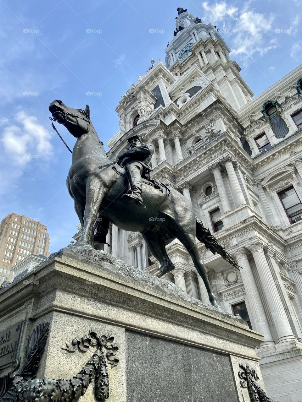 Looking upward at a concrete statue of a man on a horse with an ornate concrete building behind it