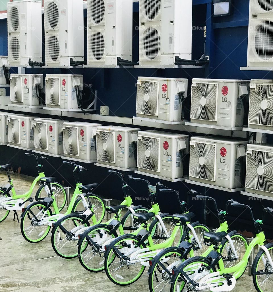 Singapore city green bicycles in a row near lot of LG AC outdoor units 