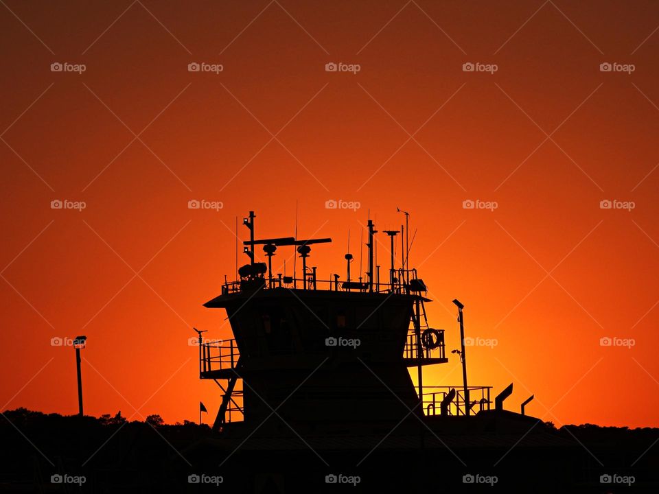 Tug boat on the Gulf of Mexico silhouetted against a magnificent sunset and orange sky. 