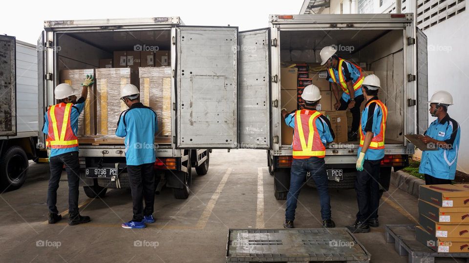 Workers are loading goods into container trucks for delivery to customers