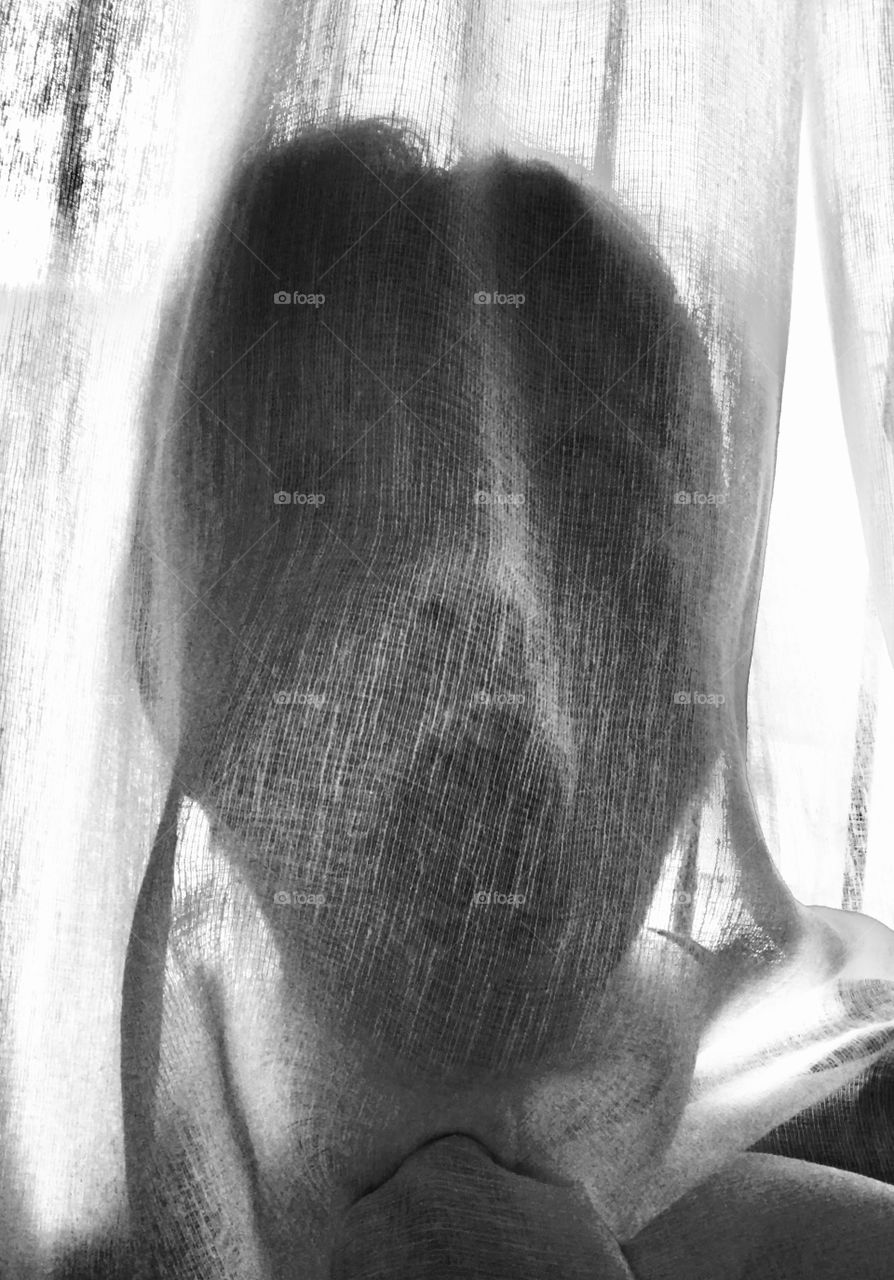The model is behind a curtain with her mouth and eyes wide open. The idea of photography is to look like a ghost or something similar to a ghost that is very scary.