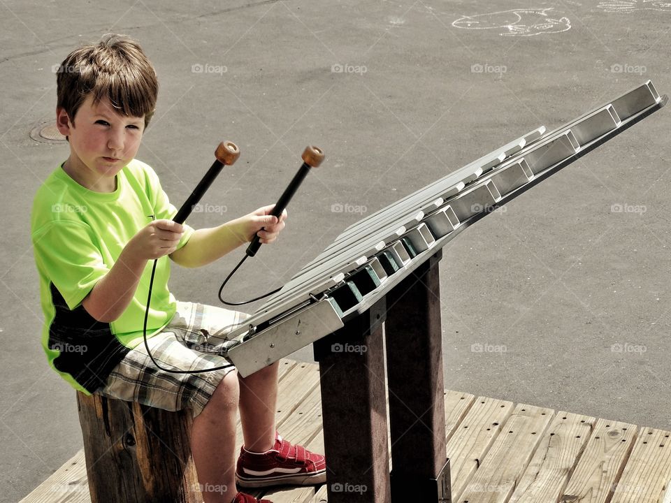 Young Street Musician. Boy Playing A Large Metal Xylophone
