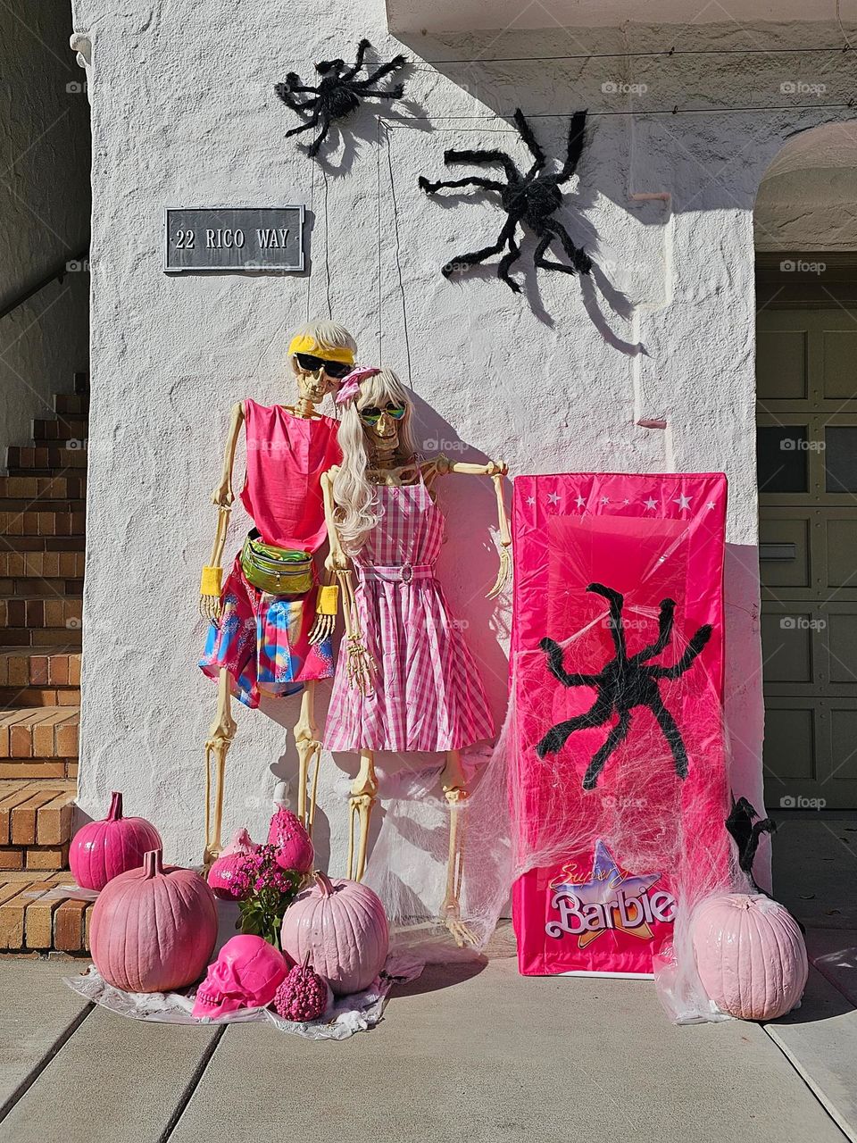 Cute and creative fall Halloween decorations in San Francisco California based on the Barbie and Ken dolls adorning a home, with vibrant pink adorned skeletons and pumpkins 