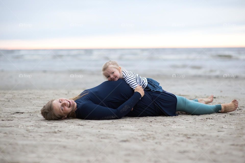 Pregnant mother and daughter on the beach