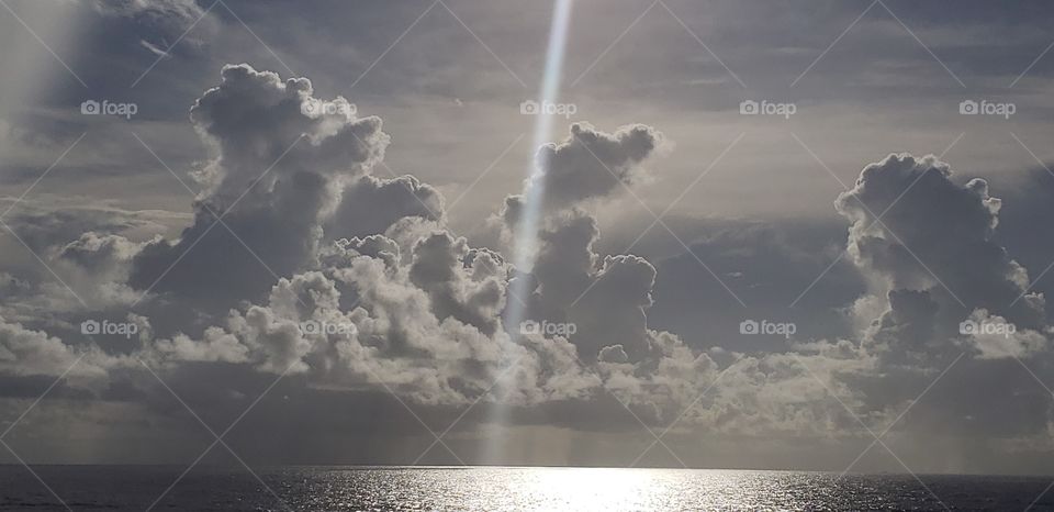 sunbeams on the deep blue Caribbean ocean surrounded by tall clouds and rain