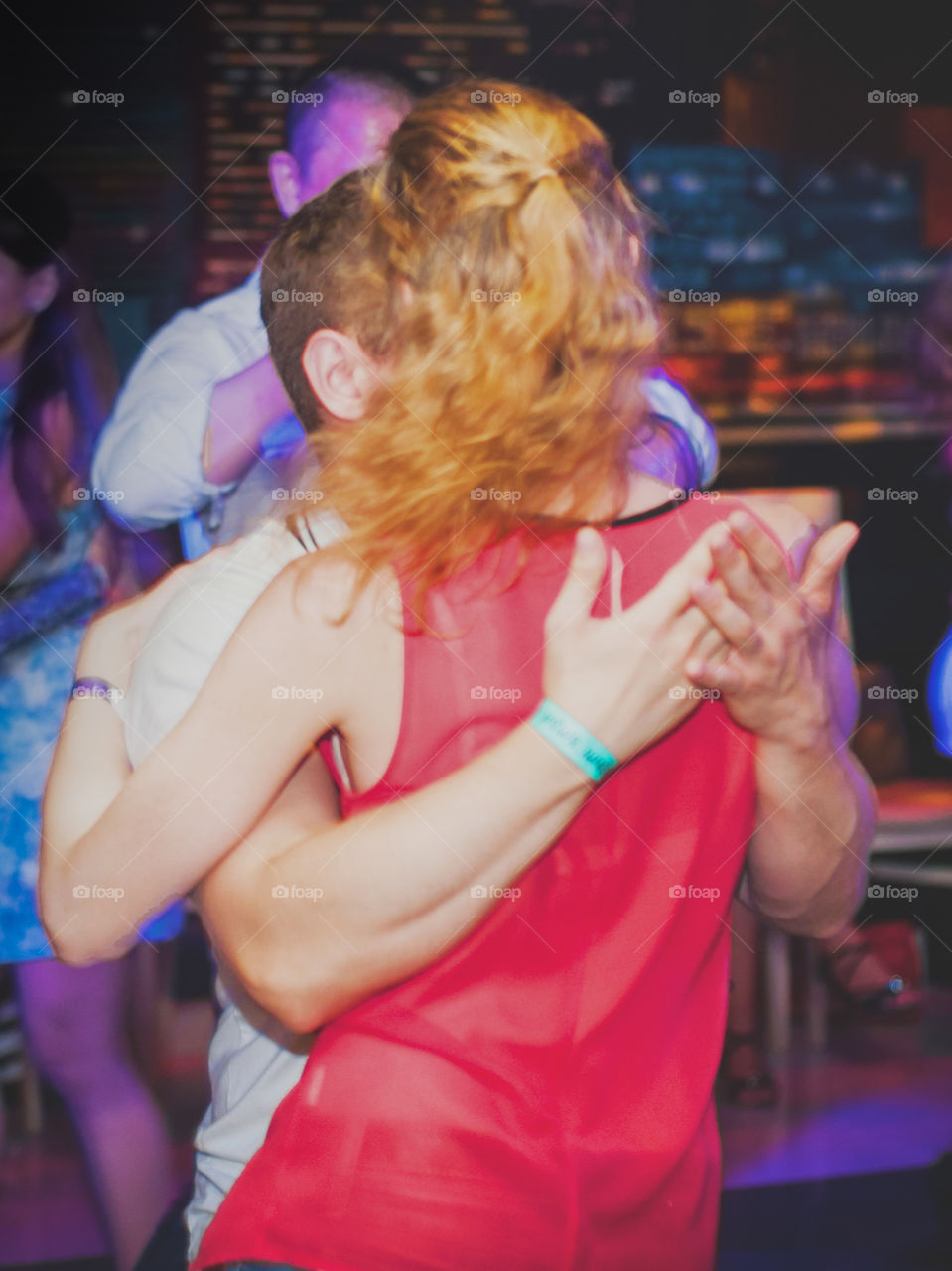 couple dancing in the club, photo taken from behind, lady in red blouse 
