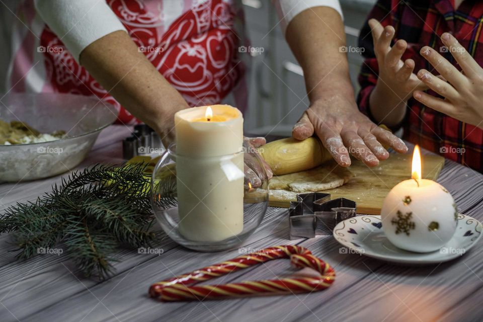 Christmas pastries, a woman's hand prepares gingerbread in the kitchen. Gifts and candles on a wooden table